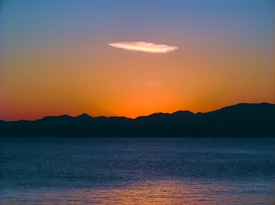 身影在夕阳山附近的水域
